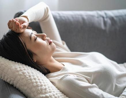 体調不良で寝込む若い女性 体調不良で寝込む若い女性の写真