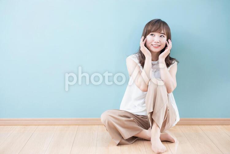肌に触れながら笑顔で考え事をする若い女性 美容,保湿,肌の写真素材