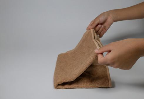 茶色のタオルを畳む手元のクローズアップ タオル,畳む,手の写真素材