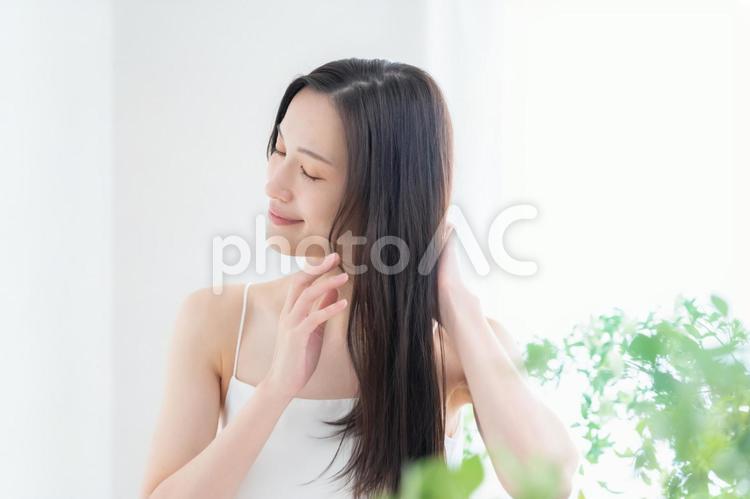 緑の中でヘアケアをする若い女性 ヘアケア,ビューティー,育毛の写真素材