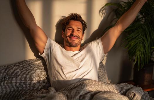 朝日を浴びて伸びをする男性の写真