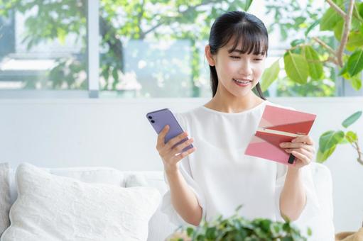 リビングで貯金通帳を見る若い女性 リビングで貯金通帳を見る若い女性 女性,リビング,ライフスタイルの写真素材