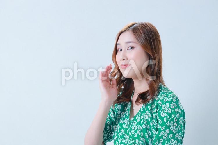 頬に手をかざす緑色のワンピースを着た女性 女性,日本人,若いの写真素材
