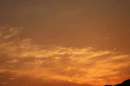 オレンジ色の夕空と黒いシルエットの山 オレンジ色の夕空と黒いシルエットの山の写真