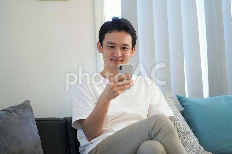 ソファで携帯を見る男性 男性,ビジネスマン,テレワークの写真素材