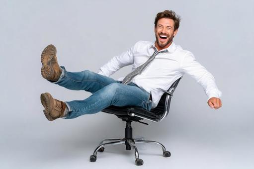 オフィスチェアで楽しげに笑うビジネスマン オフィスチェアで楽しげに笑うビジネスマンの写真