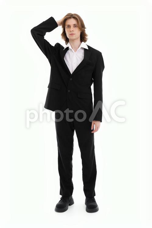 右手で頭を押さえる黒いスーツの男性 男性,真顔,立つの写真素材