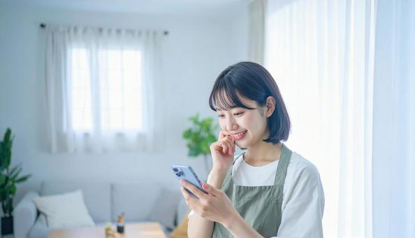 スマホでポイ活する笑顔の女性 スマホでポイ活する笑顔の女性の写真