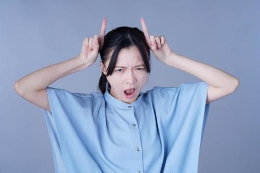 鬼ポーズをする青い服の女性の写真