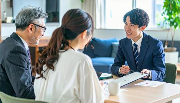 男性営業マンの説明を聞く親子 男性営業マンの説明を聞く親子の写真