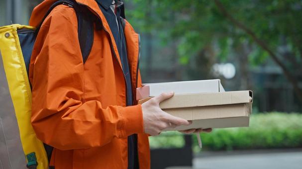 屋外でピザのデリバリーをする横向きの男性 配達,デリバリー,配送の写真素材