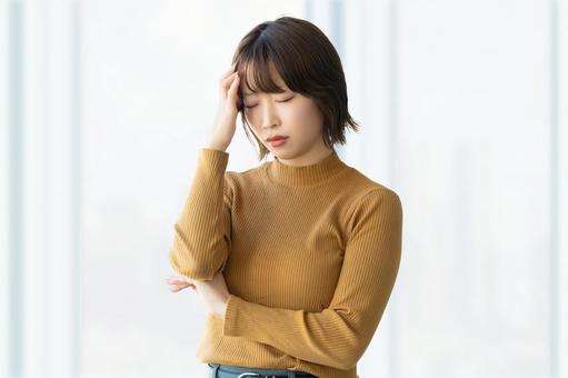 頭を抑えて悩む女性・ビジネスウーマン 女性,考える,悩むの写真素材