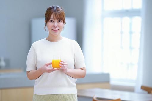 笑顔でオレンジジュースのグラスを持つ女性 女性,オレンジジュース,グラスの写真素材