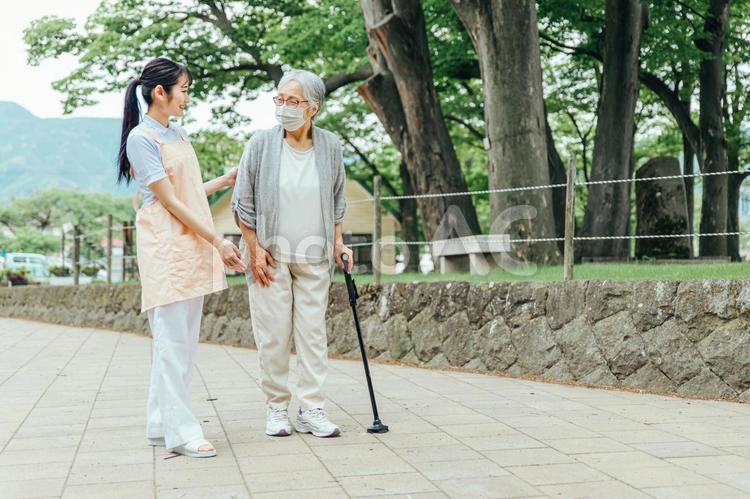 高齢者をサポートするエプロン姿の女性（杖） 介護,介護福祉士,介護士の写真素材