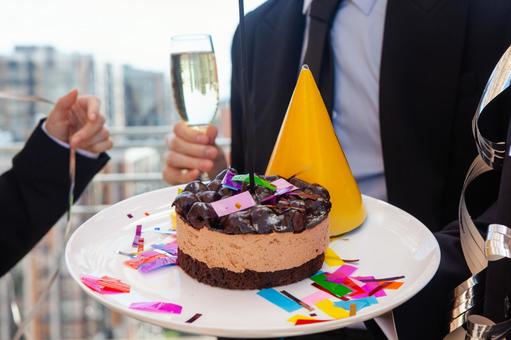 中央にケーキがのったプレートとシャンパンを持つ手元 ケーキ,お祝い,イベントの写真素材