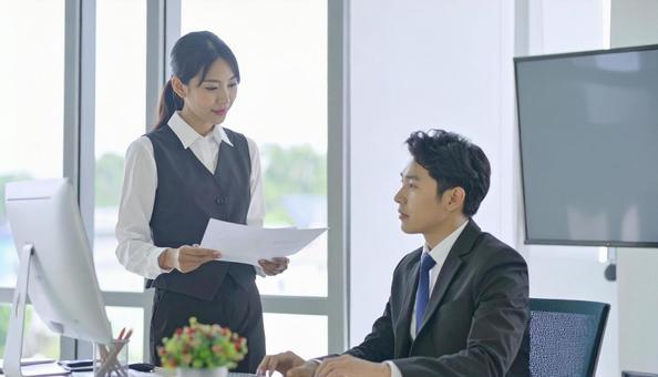 上司に報告する女性社員の写真