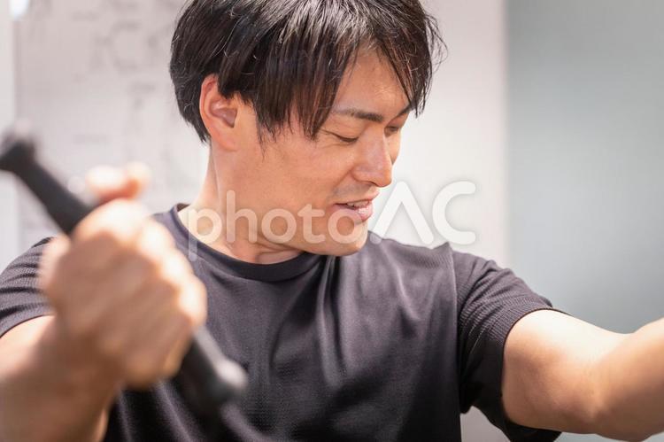 スポーツジムでケーブルマシンを使う男性 ケーブルマシン,ケーブル,ワークアウトの写真素材