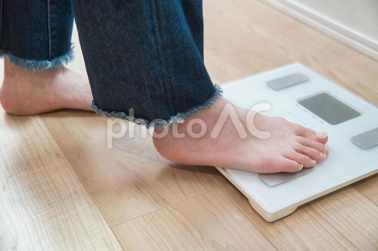 リビングで体重計にそっと足を乗せる女性 体重計,体重管理,健康維持の写真素材
