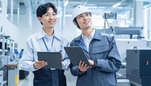 工場でタブレットで製品を検査する作業員 工場でタブレットで製品を検査する作業員の写真