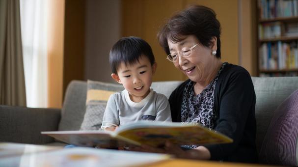 孫に絵本を読み聞かせる祖母 孫に絵本を読み聞かせる祖母の写真