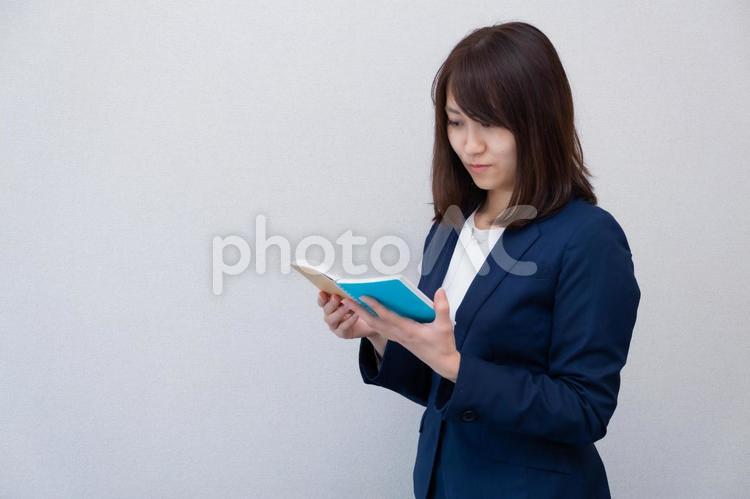 メモ帳を見ているスーツの女性 女性,スーツ,メモ帳の写真素材
