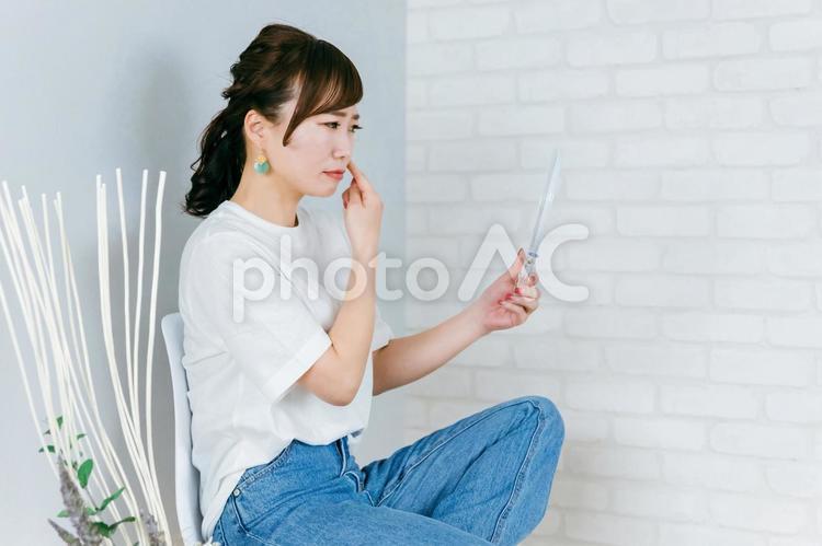 椅子に座りながら目を気にするアジア人女性 目,視力,コンタクトレンズの写真素材