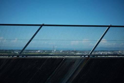 金網と青空、遠景の街並み 金網,フェンス,青空の写真素材