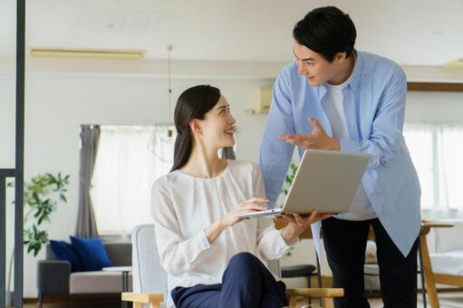 ノートパソコンを持って会話するカップル 夫婦,カップル,会話の写真素材