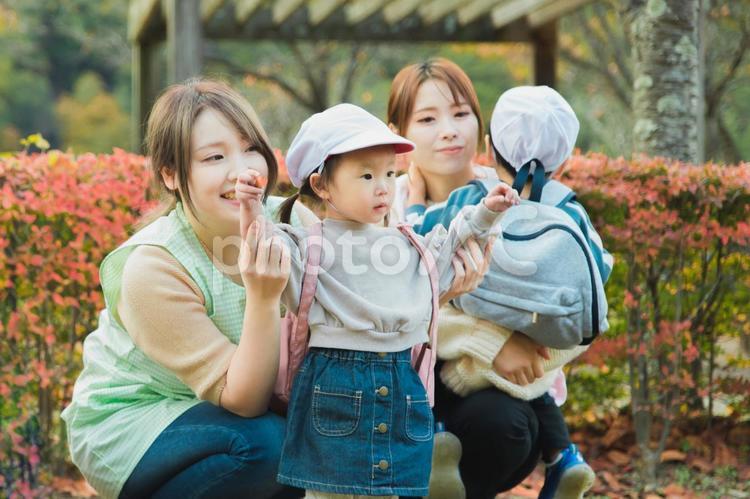 公園を散歩・遠足する保育士の女性と園児 保育園,託児所,幼稚園の写真素材
