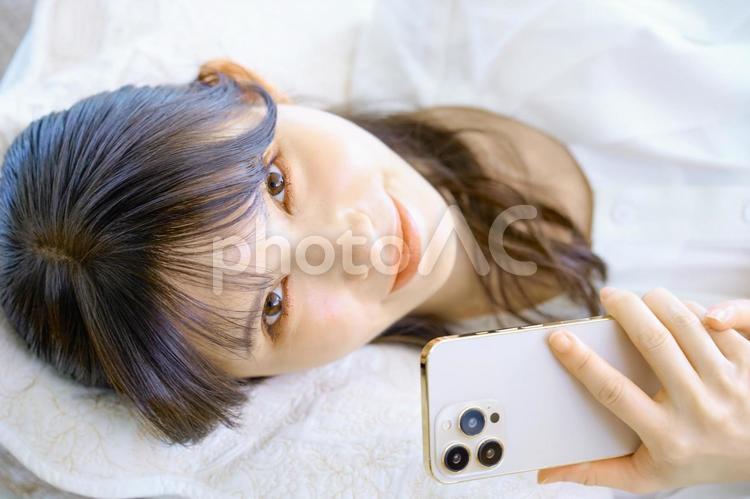 寝転がる　スマホを見る女性　主婦 スマホ,女性,主婦の写真素材