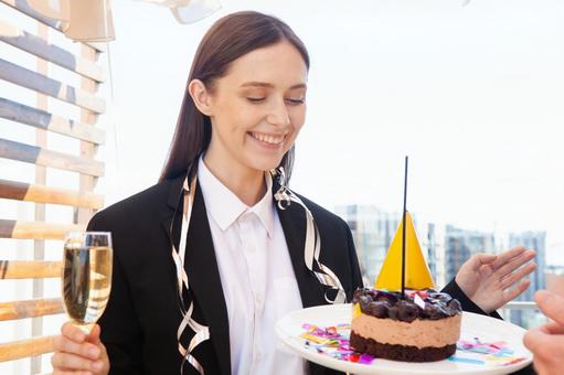 シャンパンを持ちケーキを見つめる笑顔の女性 女性,外国人,ビジネスの写真素材