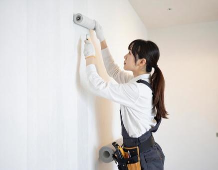 内装施工で壁紙を貼る女性の大工さんの写真