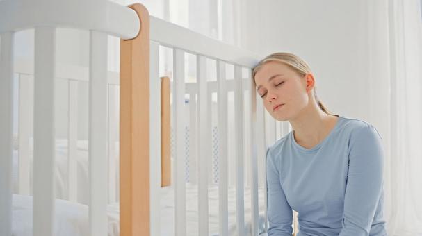 ベッドの柵に頭を付け眠る女性 ベッドの柵に頭を付け眠る女性 女性,育児疲れ,眠るの写真素材