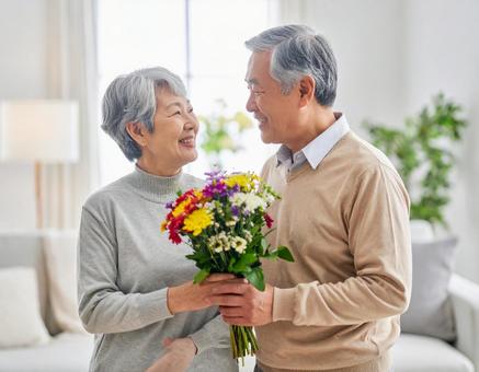 記念日に花束を贈る夫のシニア夫婦 記念日に花束を贈る夫のシニア夫婦の写真