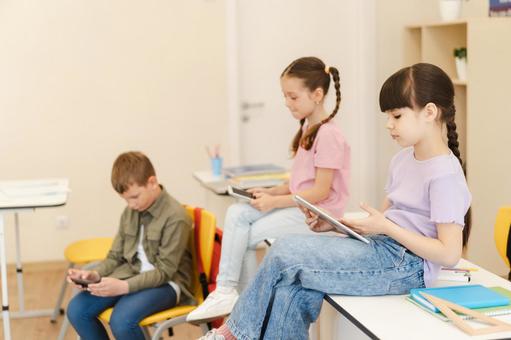 タブレットと携帯を見る生徒たち 男の子,女の子,子どもの写真素材