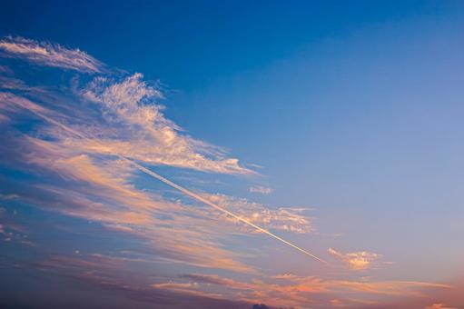 オレンジに染まる夕焼け空と飛行機雲 オレンジに染まる夕焼け空と飛行機雲の写真