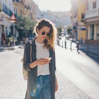 街中でスマホを見る女性の写真