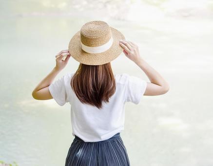 白いTシャツに麦わら帽子を被った女性 白いTシャツに麦わら帽子を被った女性の写真