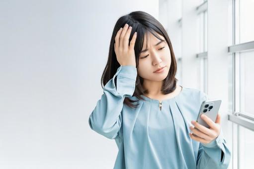 スマホを見て考える女性・ビジネスウーマン スマホを見て考える女性・ビジネスウーマン 女性,困る,考えるの写真素材