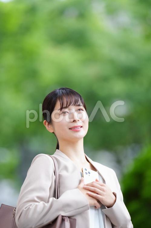 携帯を持って遠くを見ている女性 女性,人物,大学生の写真素材