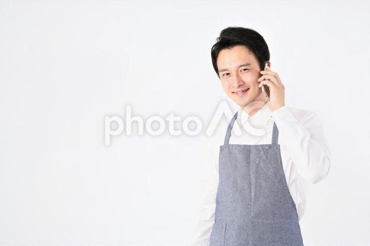 携帯を持つエプロンをつけた日本人男性 飲食店,スタッフ,店員の写真素材