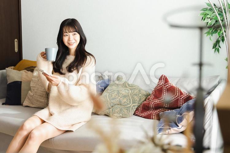 ソファーでくつろぐ若い女性 女性,スマートフォン,ライフスタイルの写真素材