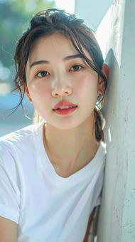 白いTシャツの女性が壁際でポーズをとる 白いTシャツの女性が壁際でポーズをとるの写真