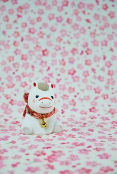 可愛い馬の置物と花柄の背景の年賀状素材の写真