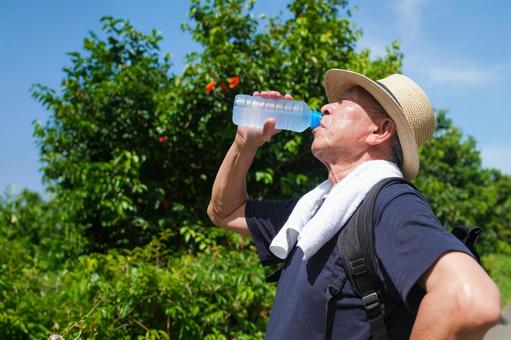 ペットボトルの水を飲む老人 ペットボトルの水を飲む老人の写真