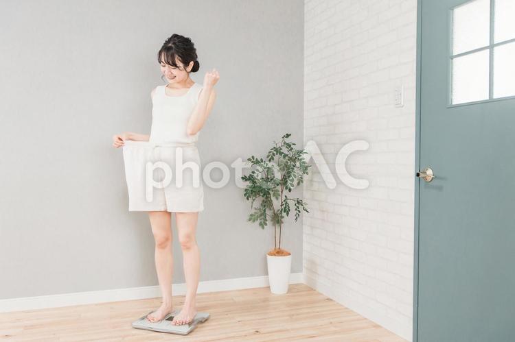 体重計に乗るスリムなアジア人女性 ダイエット,サイズダウン,ウエストの写真素材