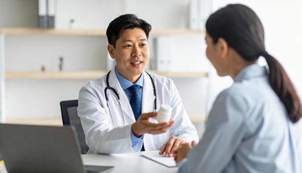 患者に対して簡単な服薬指導を行う男性医師 患者に対して簡単な服薬指導を行う男性医師の写真