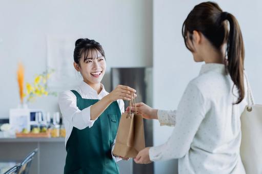 商品を渡す若い女性 商品を渡す若い女性の写真