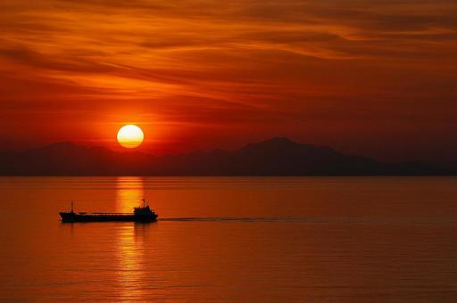夕焼けに染まる海と一艘の船 夕焼けに染まる海と一艘の船の写真
