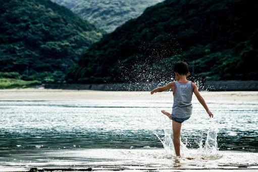 <素材>夕暮れの海で水遊びをする男の子 <素材>夕暮れの海で水遊びをする男の子の写真